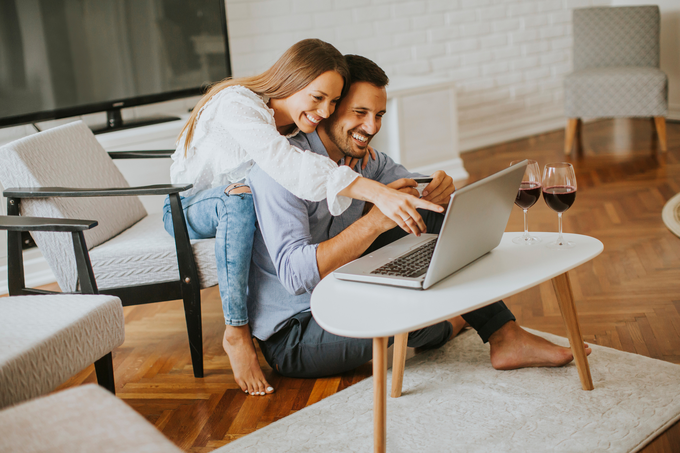 Cheerful Couple Searching Internet on Laptop at Home